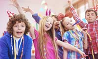 Strahlende Kinder mit Partyhüten und Luftschlangen